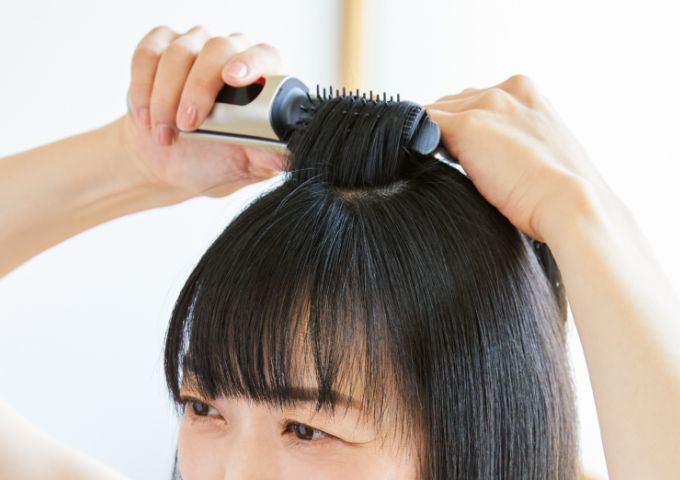 トップ部分の根元をブラッシングする女性